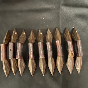 May include: A collection of nine antique calligraphy brushes. Each brush features a dark brown wooden handle with a cylindrical grip and a diamond-shaped metal tip. The bristles are a dark brown color.