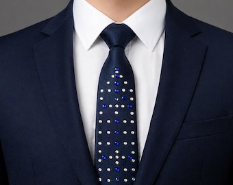 May include: A navy blue suit jacket with a white collared shirt and a navy blue tie. The tie features a pattern of white and blue dots. The suit is tailored and appears to be made of a smooth fabric.