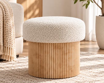 May include: A round ottoman featuring a textured cream-colored bouclé fabric seat atop a cylindrical base constructed from vertical light-toned wooden slats. The text Elexynest is visible in the upper left corner of the image.