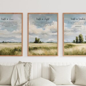 Peut inclure: Trois cadres muraux présentant des peintures de paysages avec des champs dorés sous un ciel nuageux. Chaque affiche porte le texte Walk in Love, Walk in Light et Walk in Wisdom, accompagné de versets bibliques en police sombre sur fond clair.