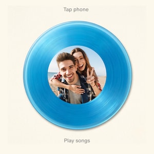 May include: A blue circular graphic featuring a photo of a smiling couple. The graphic has the words "Tap phone" at the top and "Play songs" at the bottom. The image is set against a light beige background.