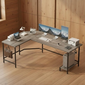 May include: L-shaped grey desk with black metal legs. The desk features three computer monitors, a laptop, a printer, and a computer tower. A brown leather briefcase hangs from the side.