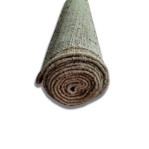 Peut inclure: Tapis de sol enroul&eacute; avec un aspect textur&eacute; et tiss&eacute;. Le tapis est principalement de couleur beige clair avec des bords marron plus fonc&eacute;s et une extr&eacute;mit&eacute; enroul&eacute;e, r&eacute;v&eacute;lant le dessous. Le tapis est sur fond blanc.