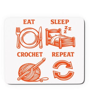 Può includere: Tappetino per mouse bianco con un'illustrazione arancione. Il design include le parole "EAT, SLEEP, CROCHET, REPEAT" con immagini corrispondenti di un piatto e posate, un letto, un gomitolo di lana con un uncinetto e una freccia circolare.
