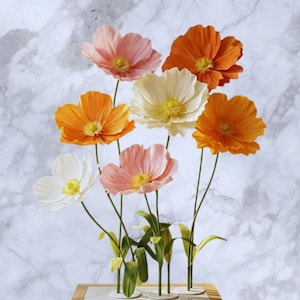 Puede incluir: Un juego de tres tazas de cerámica con un acabado moteado y mate. Las tazas son de color crema, gris claro y gris oscuro. Cada taza tiene un diseño simple y minimalista y un asa redondeada.