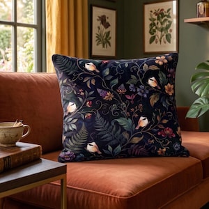 May include: A square throw pillow featuring a dark navy blue background with a detailed botanical pattern of colorful birds, green fern leaves, and various flowers in shades of pink, purple, and orange, creating a dense, intricate nature-inspired design.
