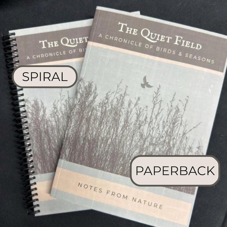 Puede incluir: Se muestran dos libros titulados "The Quiet Field: A Chronicle of Birds & Seasons". Uno es un cuaderno con espiral y el otro es un libro de bolsillo. Las portadas presentan una paleta de colores apagados con una ilustraci&oacute;n de tem&aacute;tica natural.