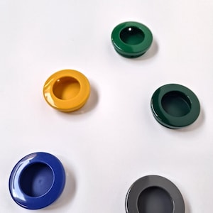 May include: Five round, recessed cabinet pulls in various colors: yellow, green, dark green, blue, and gray. Each pull has a circular design with a smooth, glossy finish, perfect for drawers or cabinets.