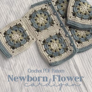 Könnte beinhalten: Eine Häkeljacke aus quadratischen Motiven mit Blumenmustern in Creme, Salbeigrün und Staubblau. Das Kleidungsstück hat eine Knopfleiste auf der Vorderseite mit passenden blauen Knöpfen. Text: Crochet PDF Pattern Newborn Flower cardigan.