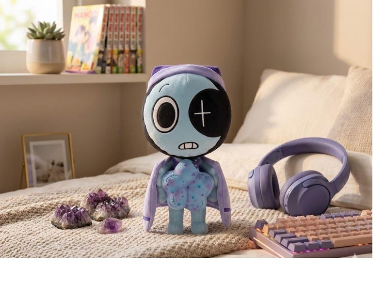 Pode incluir: Uma boneca de pel&uacute;cia com um rosto azul claro, um tapa-olho preto e uma cruz. Ela usa uma capa roxa e segura um objeto em forma de estrela. Cristais de ametista, um teclado e fones de ouvido tamb&eacute;m s&atilde;o vis&iacute;veis.