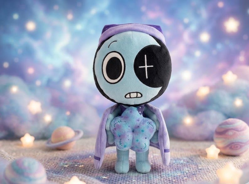 Pode incluir: Boneca de pel&uacute;cia com rosto azul claro, tapa-olho preto e touca roxa. Possui uma almofada em forma de estrela e uma capa roxa. O fundo apresenta um c&eacute;u sonhador com estrelas e planetas.