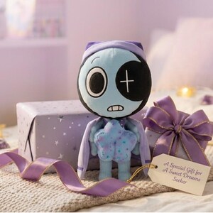 Pode incluir: Uma boneca de pel&uacute;cia com um rosto azul, um tapa-olho preto e um corpo em forma de estrela. Ela est&aacute; segurando uma estrela e est&aacute; ao lado de uma caixa de presente embrulhada com um la&ccedil;o roxo e uma etiqueta que diz "A Special Gift for A Sweet Dreams Seeker."