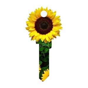 May include: A key-shaped decorative item featuring a vibrant sunflower design. The sunflower has bright yellow petals and a dark brown center, with green foliage forming the key's stem. A white circular hole is at the top.