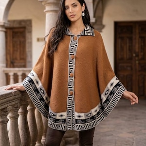 Könnte beinhalten: Ein brauner Strickponcho mit Umlegekragen, drei großen runden Knöpfen auf der Vorderseite und einem breiten Saum mit geometrischem Muster in Schwarz, Weiß und Grau. Der Stoff hat eine strukturierte Oberfläche mit kleinen erhabenen Details.