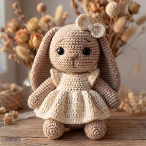 Peut inclure: Une poupée lapin en crochet beige avec de longues oreilles, des yeux en plastique noir et un nez brodé. Le lapin porte une robe en crochet couleur crème avec des manches à volants et un petit nœud assorti fixé sur le haut de la tête.