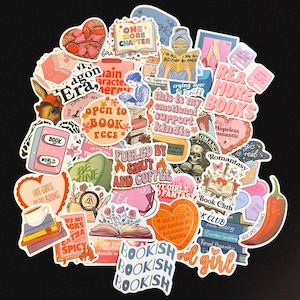 May include: A selection of colourful stickers with book-themed designs. The stickers feature phrases like "Read More Books," "Bookish," and "Fueled by Smut and Coffee." Various illustrations include books, hearts, and a skull.