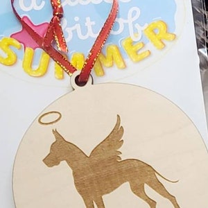 K&ouml;nnte beinhalten: Ein Holz-Anh&auml;nger mit einer Silhouette eines Hundes mit Fl&uuml;geln und einem Heiligenschein. Der Hund ist ein Deutscher Dogge. Der Anh&auml;nger ist mit dem Namen "Ruckus" graviert.