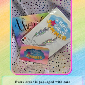 May include: A pair of silver lightning bolt earrings with a holographic glitter finish, packaged in a clear plastic sleeve with a card featuring the text a little bit of SUMMER and a small rectangular business card with the same text.