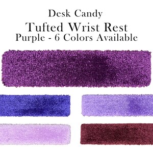 May include: Tufted wrist rests in various shades of purple, blue, lavender, and burgundy. The image displays rectangular wrist rests with a soft, textured appearance. Text at the top reads "Desk Candy Tufted Wrist Rest Purple - 6 Colors Available."