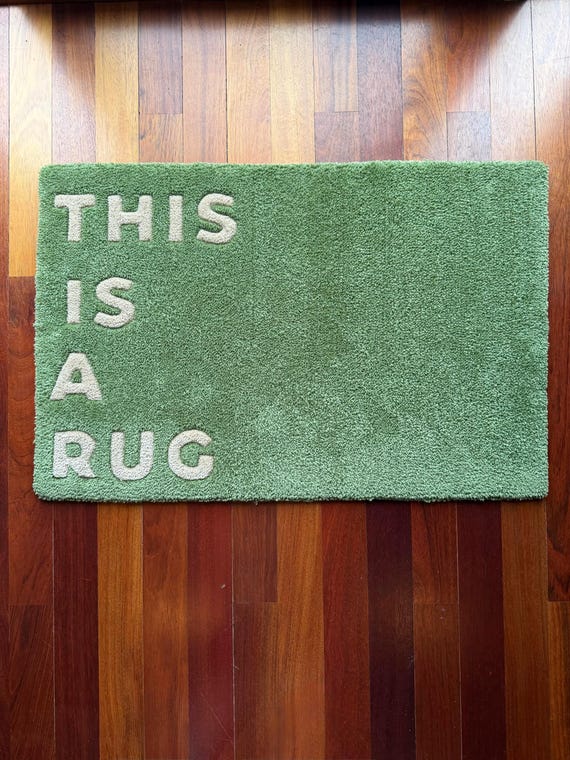 A hand-tufted rug that literally just says 'This Is A Rug' — maximalist meta humor executed in actual textile craft at gallery-piece quality.