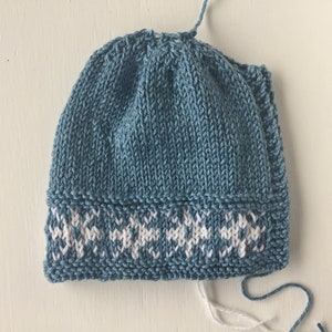 May include: A blue knitted hat with a white snowflake pattern around the brim.