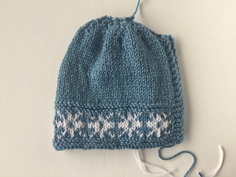 May include: A blue knitted hat with a white snowflake pattern around the brim.