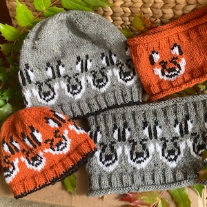 May include: Three knitted hats with a fox design. The hats are gray, orange, and gray with black trim. The hats are made with a chunky yarn and have a textured look.
