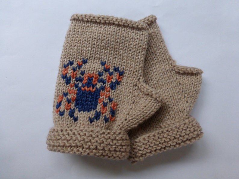 May include: A pair of beige knitted fingerless gloves with a blue, orange, and white spider design.