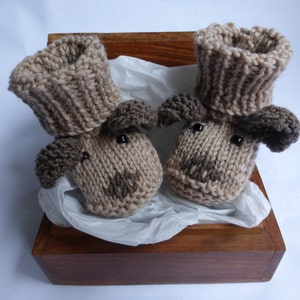 May include: A pair of knitted baby booties with brown dog faces, in a wooden box with tissue paper.