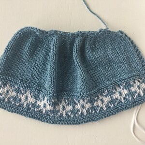 May include: A blue knitted hat with a white snowflake pattern around the brim.