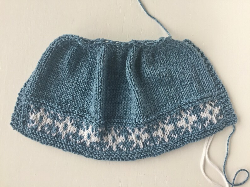 May include: A blue knitted hat with a white snowflake pattern around the brim.