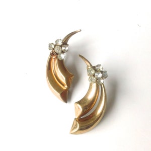 May include: A pair of gold tone earrings with a crescent moon design and clear rhinestone accents.