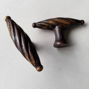 May include: Two antique bronze cabinet pulls with a twisted rope design. One is a knob, the other is a handle. Both have a dark brown finish with gold accents, and are set against a white background. These decorative pulls are ideal for furniture restoration.