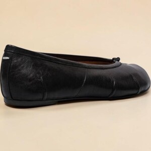 Puede incluir: Bailarinas de cuero negro con punta redondeada y un peque&ntilde;o detalle de lazo. Las bailarinas tienen un acabado liso y mate y un tac&oacute;n bajo. La talla del zapato es 39.