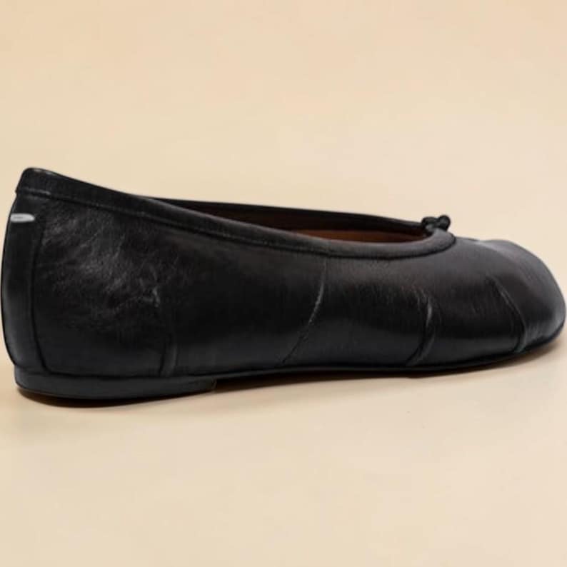 Puede incluir: Bailarinas de cuero negro con punta redondeada y un peque&ntilde;o detalle de lazo. Las bailarinas tienen un acabado liso y mate y un tac&oacute;n bajo. La talla del zapato es 39.