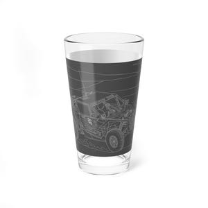 Op de afbeelding: Een helder pintglas met een rondomlopende afbeelding van een racevoertuig in een woestijnlandschap. Het voertuig is gedetailleerd met lijnen en de tekst "PRO TECH SERIES". Het glas is leeg en staat op een witte ondergrond.