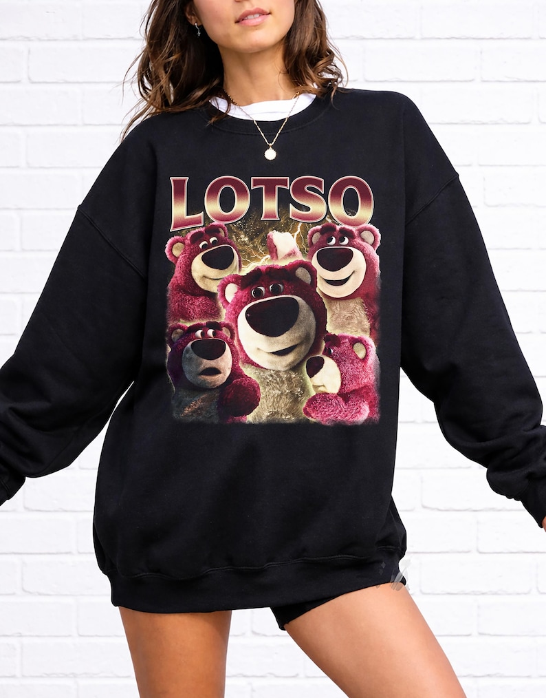 May include: Black sweatshirt featuring a graphic of Lotso, the bear character from Toy Story, with the word "LOTSO" in gold lettering. The image shows Lotso's face and other bears in shades of pink and white.