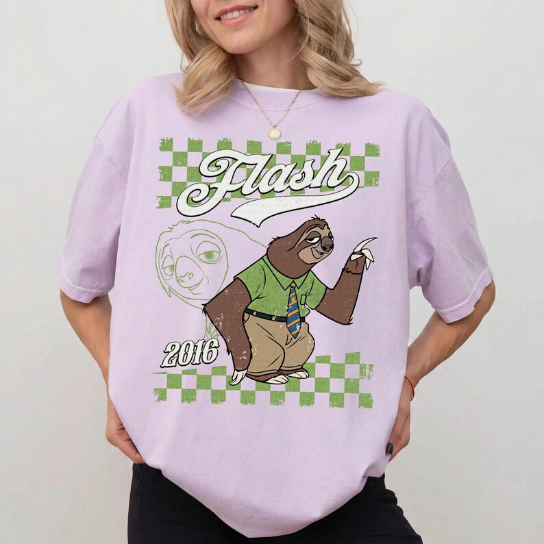 Puede incluir: Una camiseta de color morado claro con un gr&aacute;fico de un perezoso de dibujos animados que lleva una camisa verde, pantalones beige y una corbata a rayas. El dise&ntilde;o incluye la palabra "Flash" en letra cursiva blanca, el a&ntilde;o "2016" y un borde a cuadros verde y blanco.