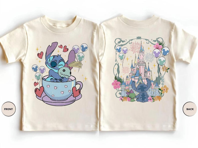 May include: A cream-colored t-shirt shown from the front and back. The front features a blue alien character sitting in a light purple teacup with hearts. The back displays the same character facing a large castle with fireworks and floral accents.