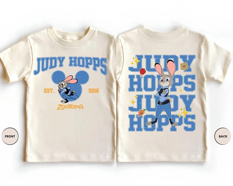 May include: A cream-colored t-shirt featuring Judy Hopps from Zootopia. The front displays the text Judy Hopps, Est. 2016, and Zootopia with a blue Mickey Mouse silhouette. The back shows Judy Hopps with the text Judy Hopps, a carrot, and a badge.