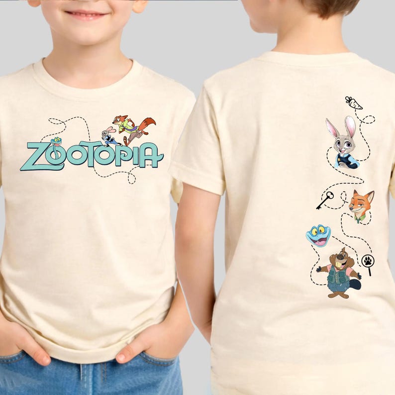 May include: A cream-colored short-sleeve t-shirt featuring the Zootopia logo and characters on the front. The back displays a vertical sequence of Zootopia characters including a rabbit, fox, sloth, and beaver connected by a dashed line path.