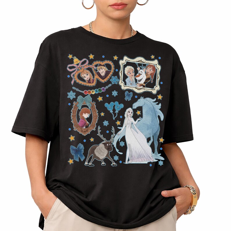 Puede incluir: Camiseta negra con un dise&ntilde;o gr&aacute;fico colorido con personajes de la pel&iacute;cula animada Frozen. El dise&ntilde;o incluye im&aacute;genes de Anna, Elsa, Olaf, Kristoff y Sven, junto con elementos decorativos como estrellas y lazos.