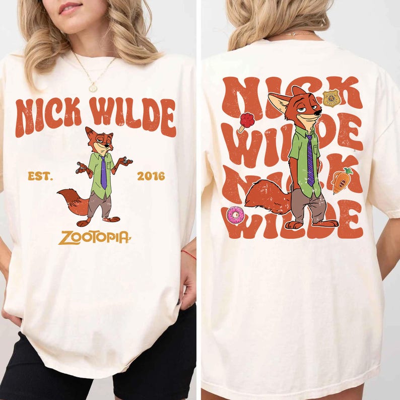 Pode incluir: Uma t-shirt em tom creme com um gr&aacute;fico da personagem Nick Wilde de Zootopia. A frente exibe a personagem com o texto NICK WILDE, EST. 2016 e ZOOTOPIA. As costas apresentam um gr&aacute;fico grande da personagem com texto repetido.