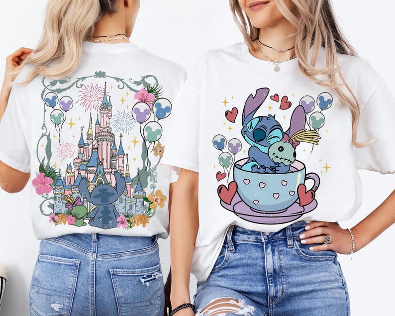 May include: Two white t-shirts featuring graphic prints. The back design shows a blue alien character and a doll in front of a castle with fireworks and balloons. The front design shows the same blue alien character sitting in a teacup with hearts.