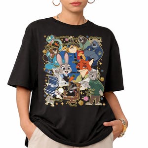 Op de afbeelding: Zwart t-shirt met een kleurrijke afbeelding van personages uit de animatiefilm Zootopia. Het ontwerp bevat Judy Hopps, Nick Wilde en andere personages. Het shirt heeft korte mouwen en een ronde hals.