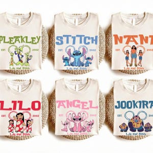Puede incluir: Seis camisetas de color blanco roto con personajes de Lilo y Stitch. Cada camiseta muestra el nombre de un personaje, el texto EST. 2002 y el logotipo de Lilo y Stitch. Los personajes incluyen a Pleakley, Stitch, Nani, Lilo, Angel y Jookiba.