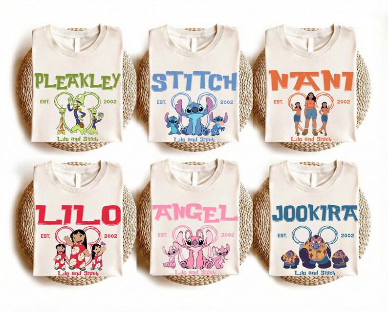 Puede incluir: Seis camisetas de color blanco roto con personajes de Lilo y Stitch. Cada camiseta muestra el nombre de un personaje, el texto EST. 2002 y el logotipo de Lilo y Stitch. Los personajes incluyen a Pleakley, Stitch, Nani, Lilo, Angel y Jookiba.
