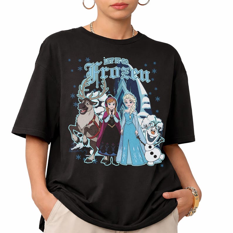 May include: Black t-shirt featuring characters from the movie Frozen, including Elsa, Anna, Olaf, and Sven. The shirt has the words "Let It Go Frozen" in blue. Snowflakes and a snowy mountain scene are also depicted.
