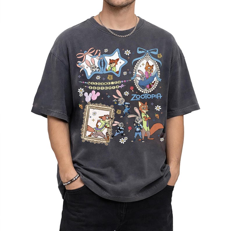 May include: A charcoal gray short-sleeve t-shirt featuring a Zootopia graphic print. The design includes illustrations of Judy Hopps and Nick Wilde within star-shaped and oval frames, with the text Welcome to Zootopia and Zootopia printed.