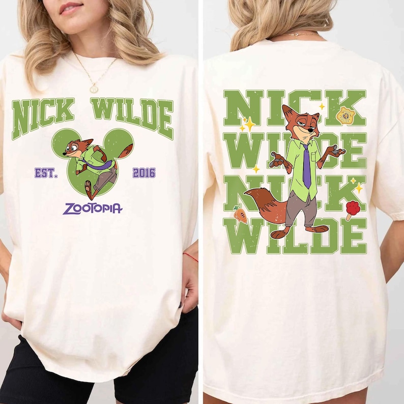 May include: An off-white t-shirt featuring Nick Wilde from Zootopia. The front displays the text NICK WILDE, EST. 2016, and ZOOTOPIA with a green Mickey-shaped icon. The back shows Nick Wilde with the text NICK WILDE in large green letters.